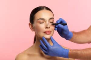 A doctor marking a woman’s nose for a rhinoplasty procedure.