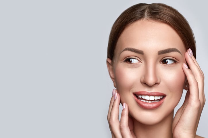 Beautiful female with clean clear skin, natural make up, and white teeth on grey background. Beauty and spa concept. Healthy skin. Horizontal