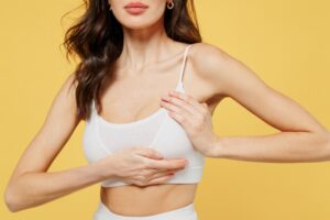 Woman in bra holding one of her breasts and thinking about breast surgery to correct asymmetry